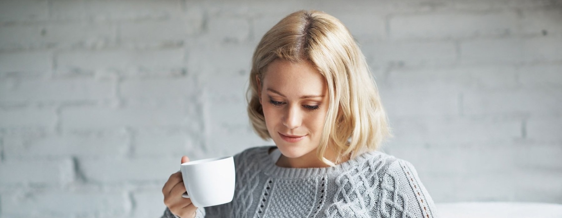 a person sitting down holding a cup looking at a tablet