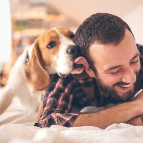 We love our furry friends a person laying on a bed with a dog