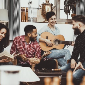 Love where you live a group hanging out in living room with guitar